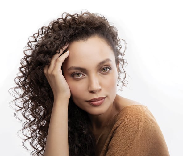Woman with curly hair, thoughtful expression.
