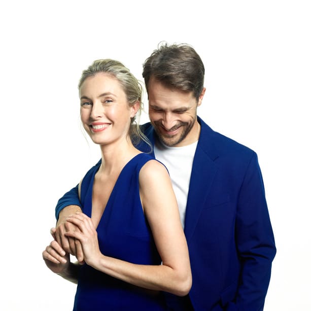 Couple smiling against white background.