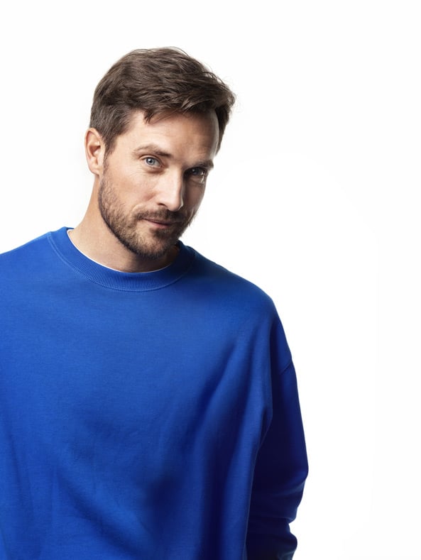 Man in blue sweatshirt, casual pose.